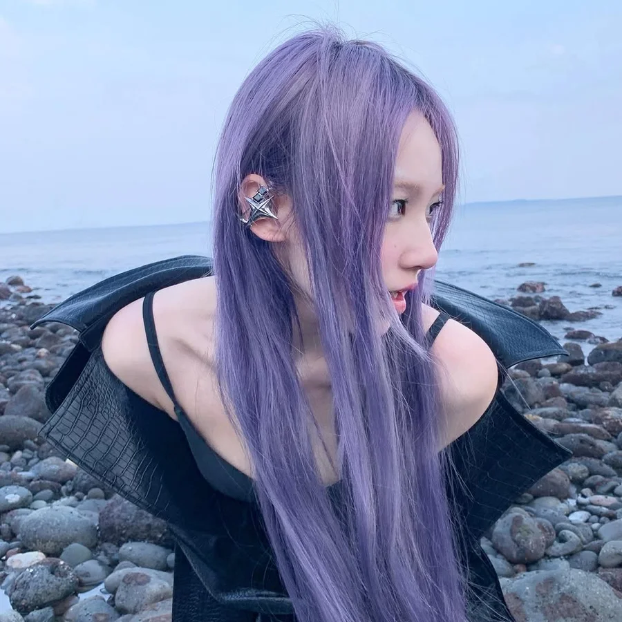 Purple-haired wearer in a black jacket with silver NEBULA earphones beside the sea